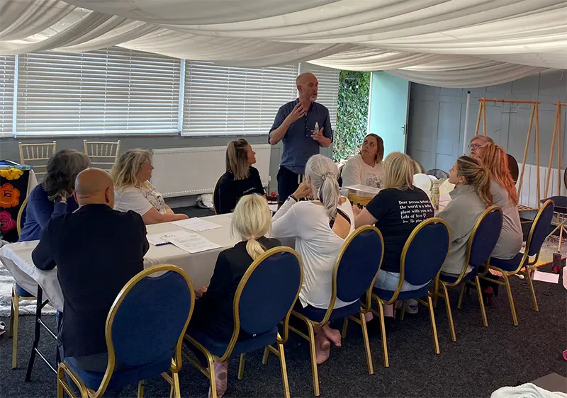 Meet the Zen Community Hub Committee Neil explaining essential oils to a group during an aromatherapy workshop.
