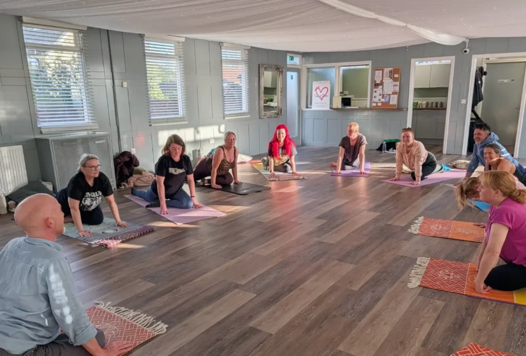A group of people doing a yoga class lead by Neil